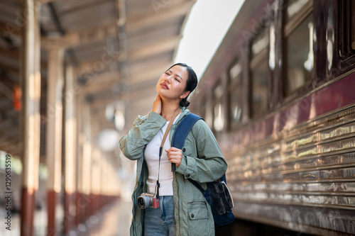 Schilderij op canvas An asian woman is looking uncomfortable while wiping sweat with her hand on the station platform