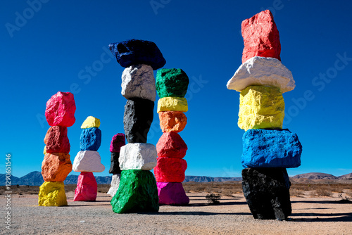 Vibrant, stacked rock formations rise against a clear desert sky, exemplifying bold colors and artistic representation of nature's creativity in a stark environment.