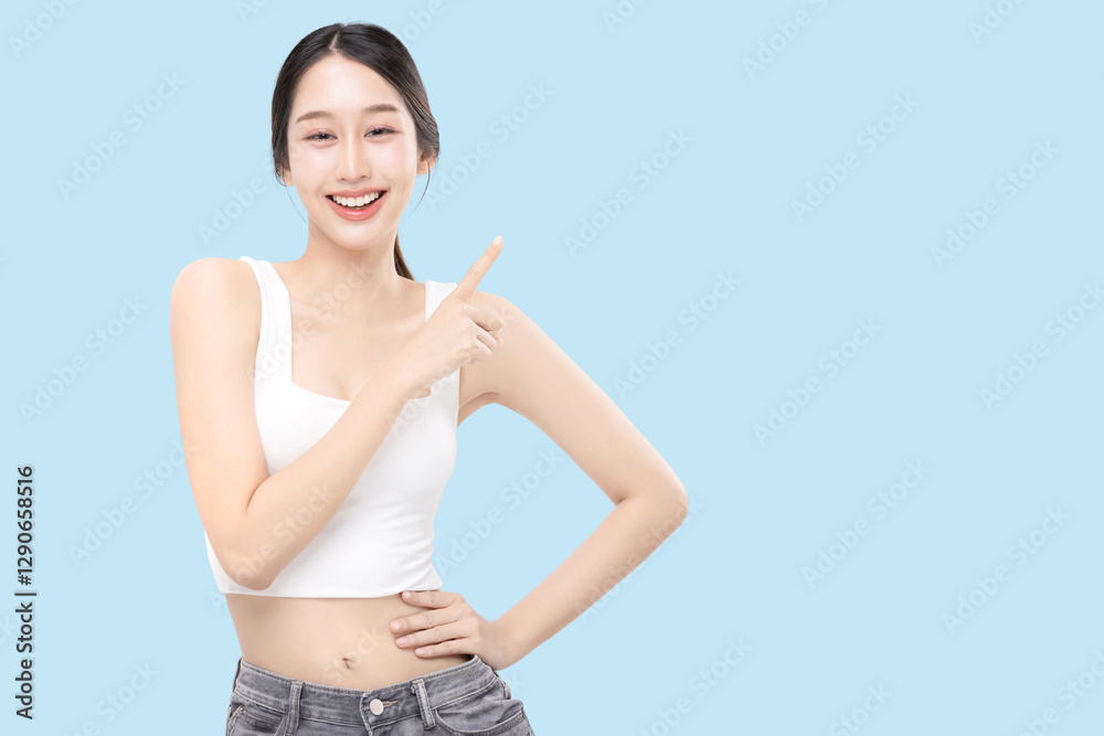 Portrait of young Asian beautiful woman with K-beauty make up style and healthy and perfect skin pointing finger to copy space isolated on blue background. Portrait of young Asian beautiful woman with K-beauty make up style and healthy and perfect skin pointing finger to copy space isolated on blue background.