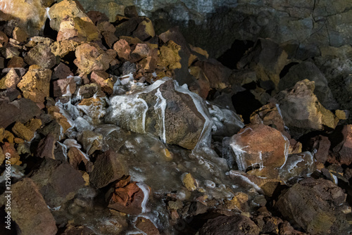 An intriguing close-up of a rocky floor featuring flowing water and vibrant mineral deposits, illustrating the dynamic processes of nature and geological beauty.