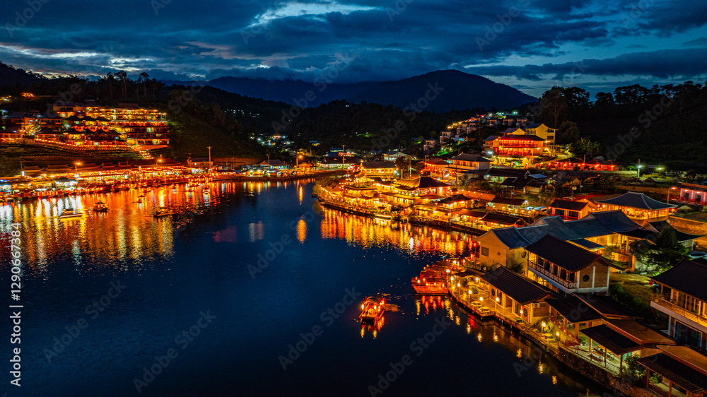 Fototapeta premium Baan Rak Thai Village at sunset reflections of houses and restaurants along the lake in Chinese-style architecture with colorful lights line the water. a popular tourist attraction in Mae Hong Son