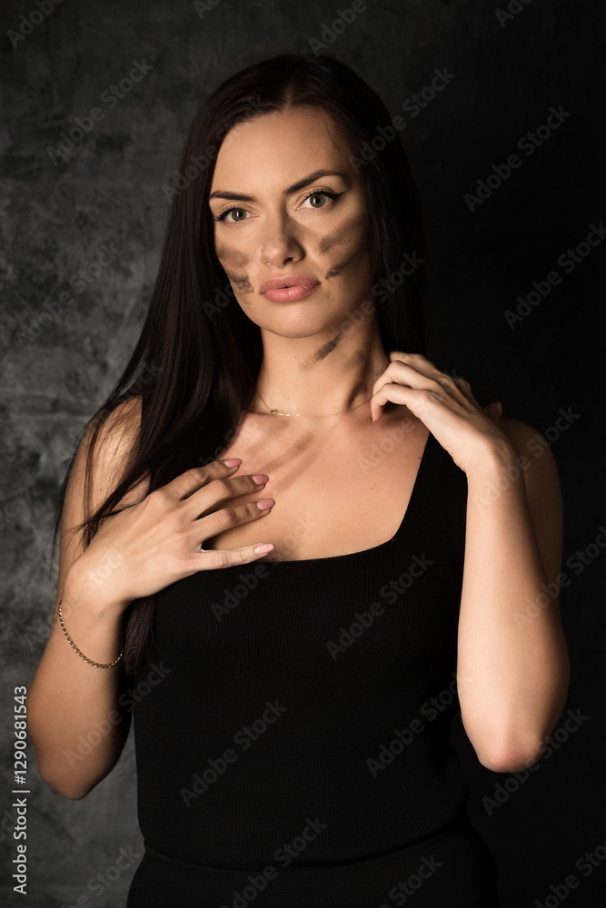 Beautiful woman in a black top applying camouflage military makeup to her body