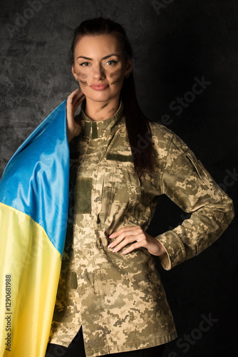 Obraz na płótnie Beautiful military woman in military uniform with camouflage makeup on her face with Ukrainian flag w salonie