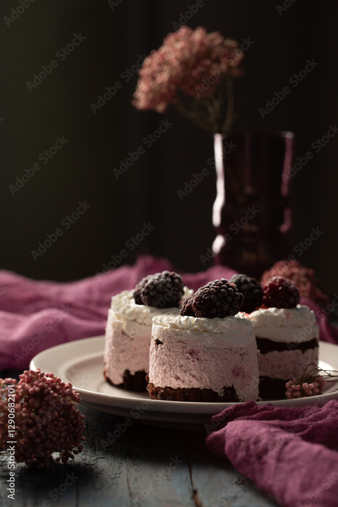 Delicious cream cakes with frozen blackberries on a plate