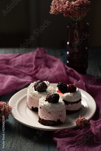 Delicious cream cakes with frozen blackberries on a white plate. Still life in a rustic style