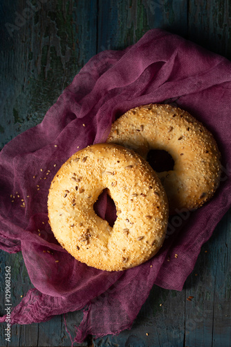 Obraz na płótnie Homemade large bagels with sesame, flax and sunflower seeds on burgundy gauze, top view w salonie