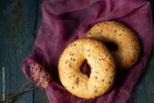 Obraz na płótnie Homemade large bagels with flax and sunflower seeds on burgundy gauze, top view w salonie
