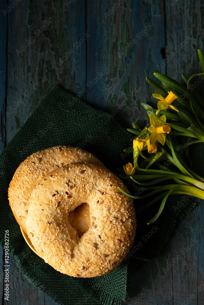 Still life in rustic style bagels sprinkled with seeds with yellow daffodils