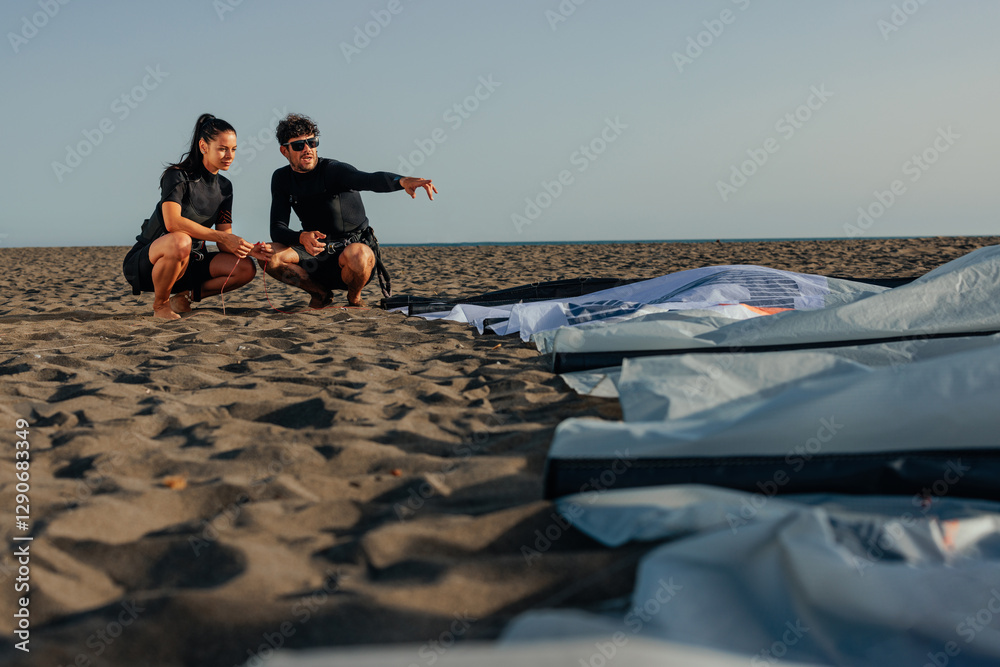 Naklejka premium Male kite surfer explaining something to his female teammate