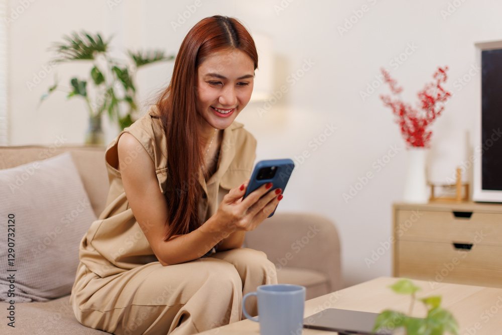 Beautiful confident asian business woman sitting on cozy couch, using funny mobile apps in living room. Woman at Home, Doing Online Shopping, Messaging Friends, Posting on Social Media Beautiful confident asian business woman sitting on cozy couch, using funny mobile apps in living room. Woman at Home, Doing Online Shopping, Messaging Friends, Posting on Social Media