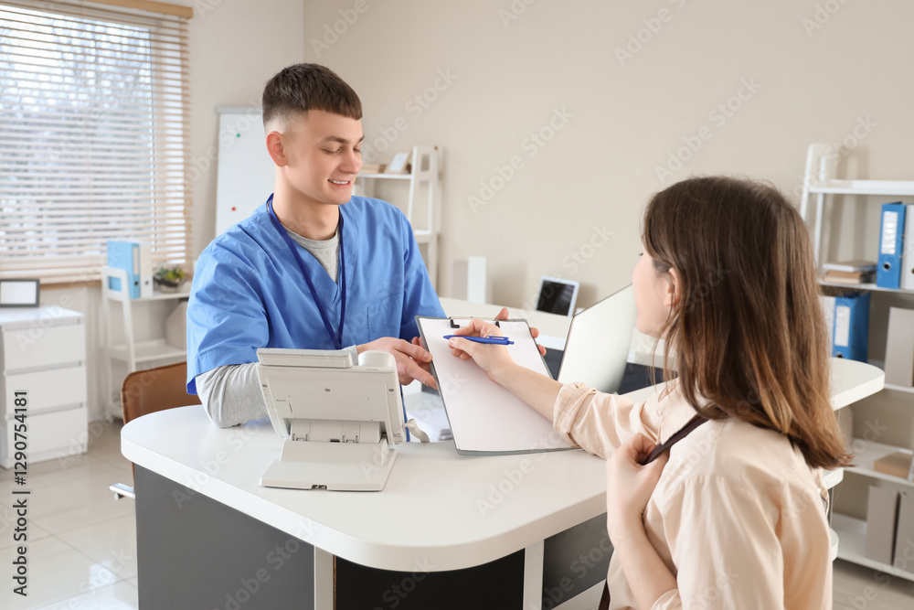 Obraz premium Male medical intern working with patient at reception desk in clinic