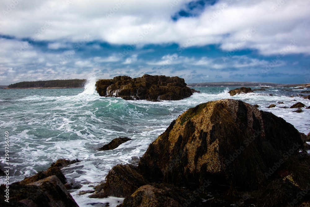 Scenic coastal view with waves crashing against rugged rocks under a partly cloudy sky Scenic coastal view with waves crashing against rugged rocks under a partly cloudy sky
