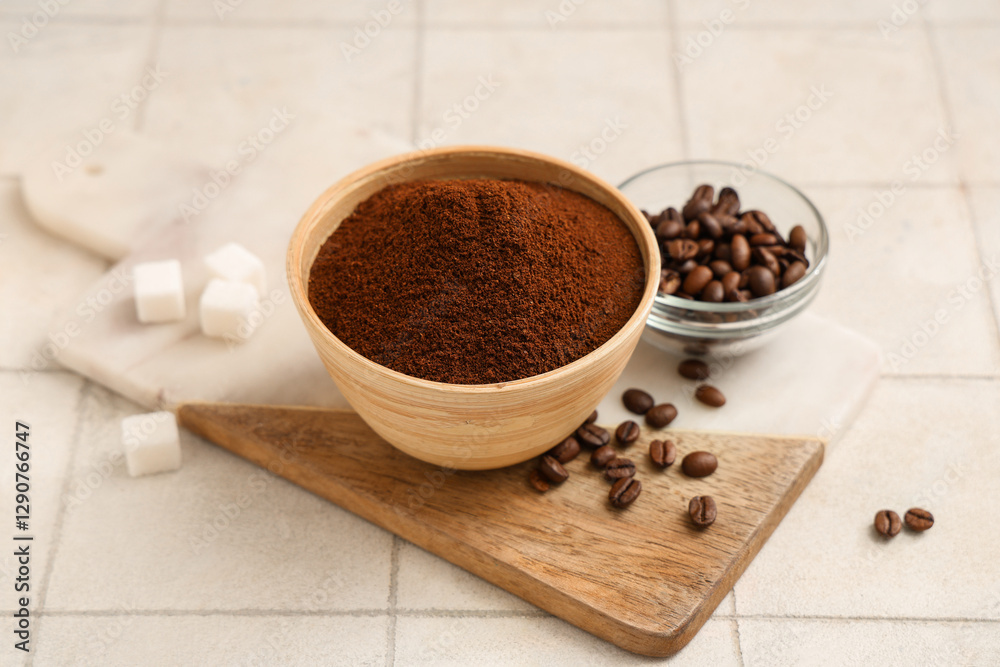 Board with bowl of coffee powder, beans and sugar cubes on white tile background Board with bowl of coffee powder, beans and sugar cubes on white tile background