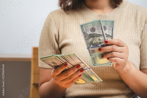 Young woman with dollars in hand. Female holding cash money in dollar banknotes. Woman holding lots of money in dollar currency at home