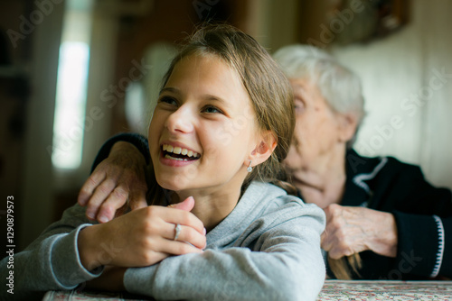 Obraz na płótnie A teenage girl and her grandmother enjoying a fun and cheerful moment together. w salonie