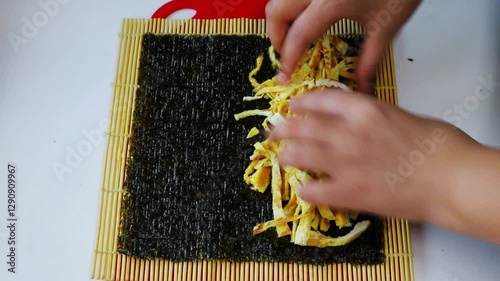 I'm making kimbap by adding rice, vegetables, and eggs to seaweed.김에 밥과 야채,계란을 넣고 김밥을 만들고있습니다.