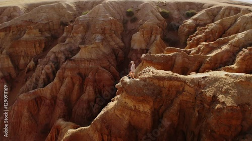 A girl walking through the Mars-like hills of Tsagaan Suvarga, Mongolia, captured in breathtaking aerial drone footage at sunset.