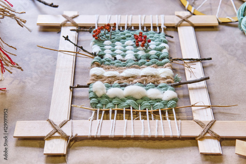 Small handmade weaving tapestry on wooden frame, featuring yarn and natural elements