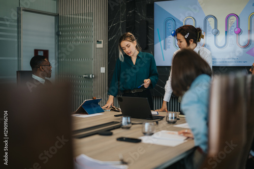A diverse group of people engaged in a productive meeting in a contemporary office. The team is collaborating, discussing, and strategizing over presentations and ideas, highlighting teamwork and