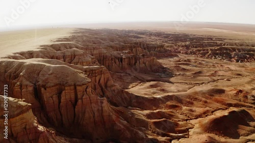 A girl walking through the Mars-like hills of Tsagaan Suvarga, Mongolia, captured in breathtaking aerial drone footage at sunset.