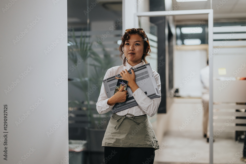 A young professional stands confidently in a modern office, holding a laptop. The scene conveys a sense of determination and readiness in a contemporary workplace setting. A young professional stands confidently in a modern office, holding a laptop. The scene conveys a sense of determination and readiness in a contemporary workplace setting.