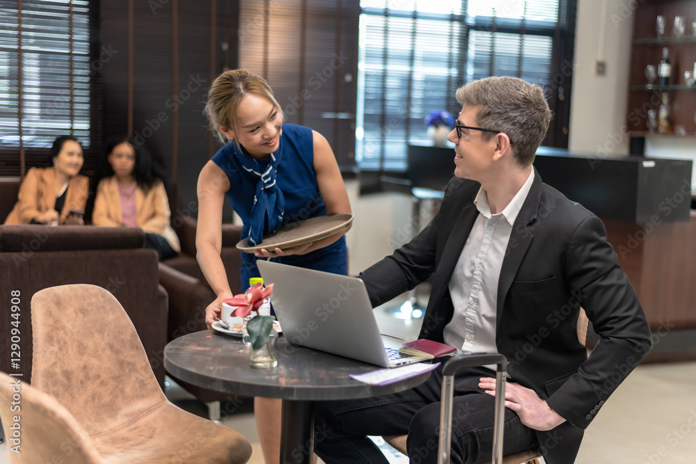 Asian waitress serving coffee to businessman in airport lounge