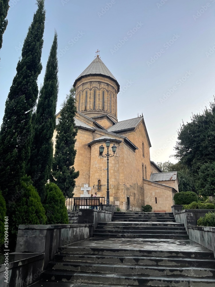 A stone church with a staircase in front, surrounded by trees, with a clear view of the sky in the background. A stone church with a staircase in front, surrounded by trees, with a clear view of the sky in the background.
