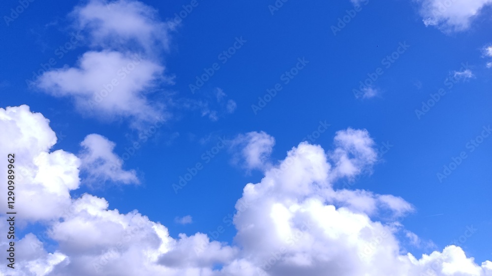 Fototapeta premium Stunning vibrant blue sky canvas adorned with fluffy white cumulus clouds. Perfect for backgrounds, websites, or illustrating concepts of freedom, serenity, and weather.