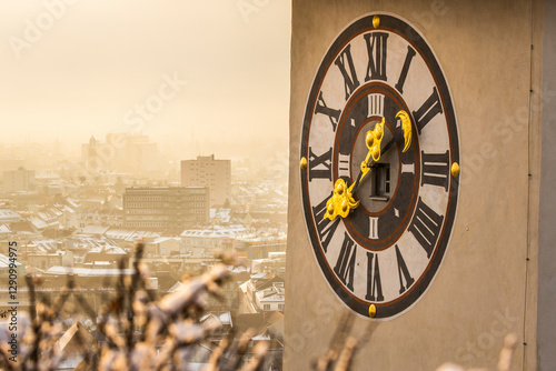 View of the beautiful clocktower at sunrise with a scenic skyline and frosty landscape, Graz, Austria.