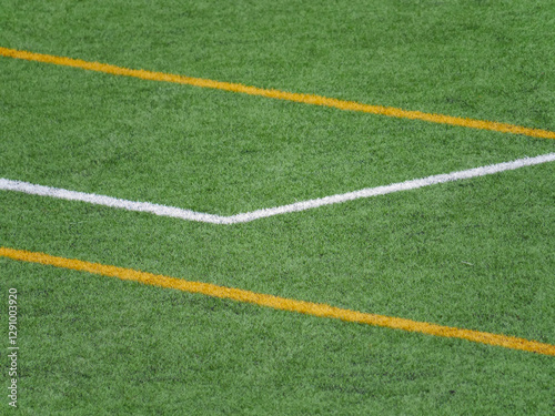 Close up of grass field with white and yellow lines in soccer field