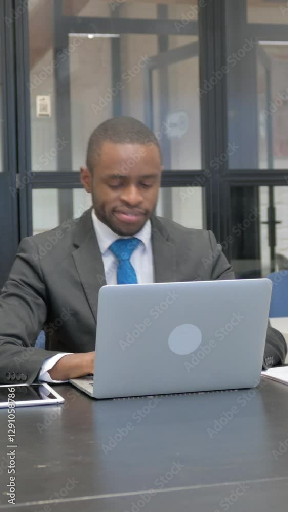 African American Businessman Smiling at Camera while Working on Laptop African American Businessman Smiling at Camera while Working on Laptop
