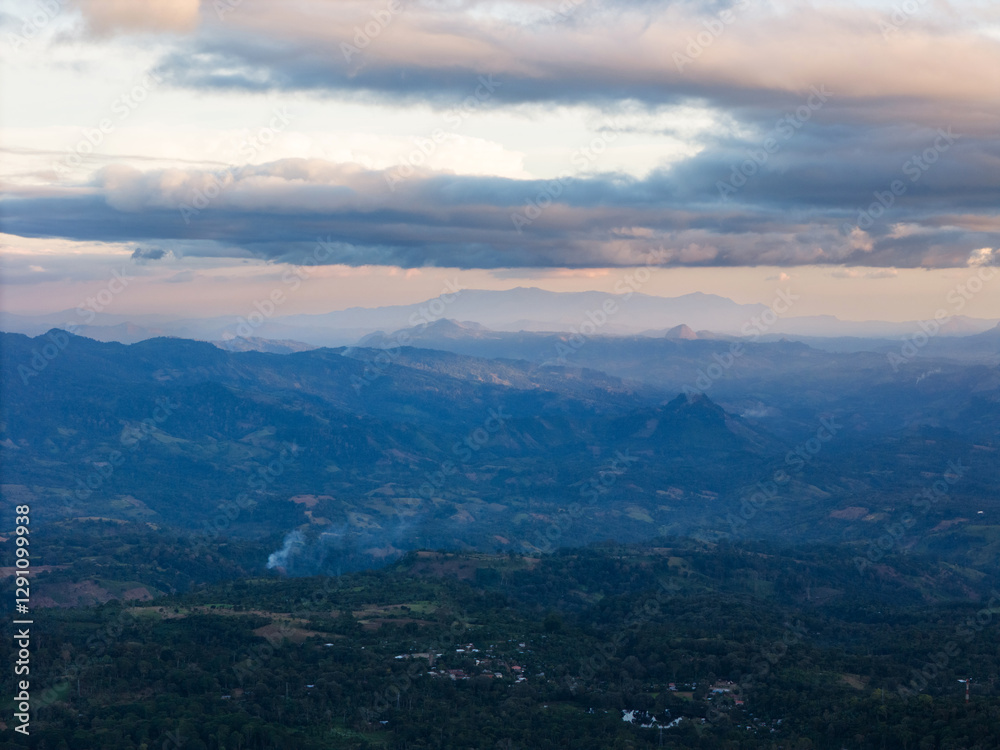 Fototapeta premium Stunning mountain landscape at dusk with smoke rising from valley below