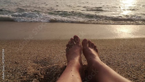 Bare feet on a sandy beach as waves roll in. 4K video, 36 seconds. Perfect for summer, relaxation, or vacation themes