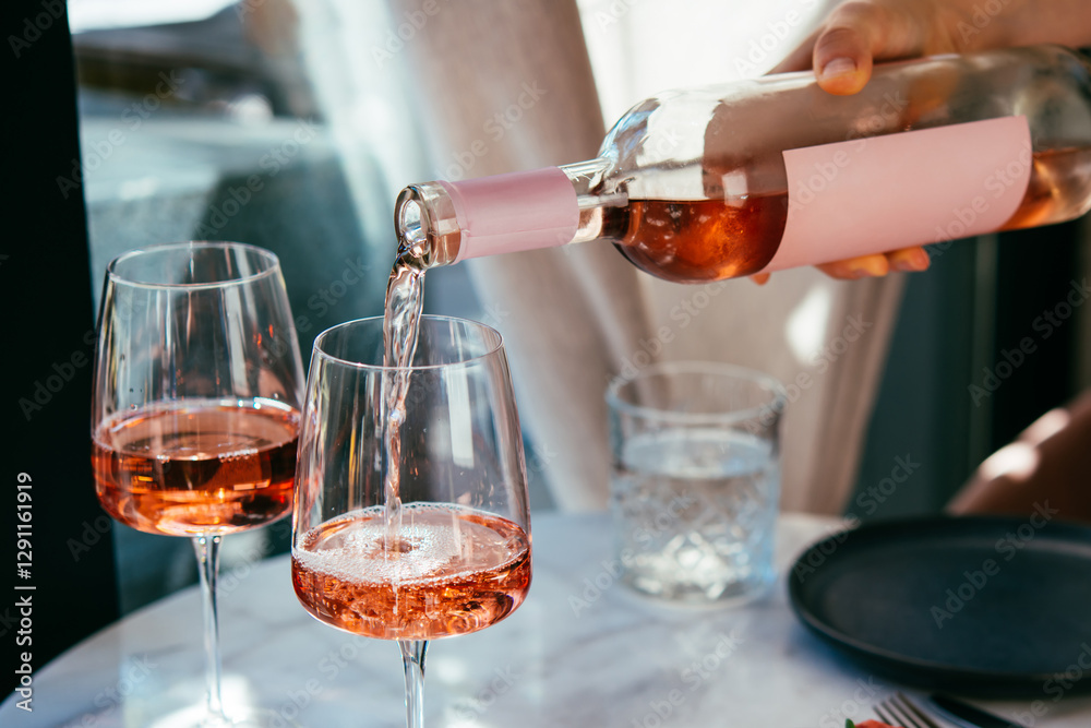 Pouring rose wine at a dinner party with friends in a bar or restaurant.