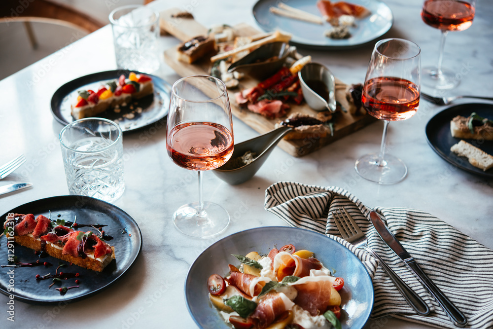 A table served for a dinner with prosciutto salad and rose wine in a bar or restaurant.