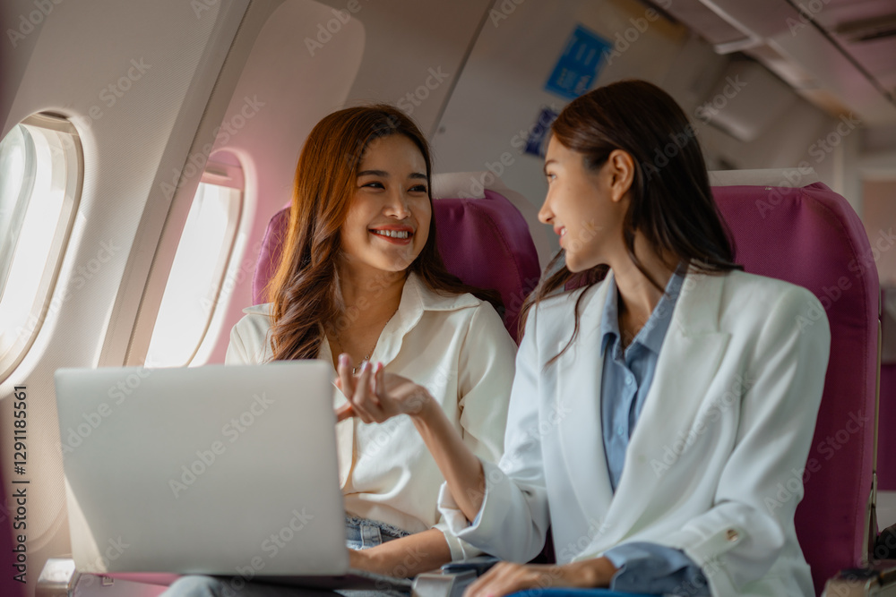 two beautiful asian female friends are traveling abroad for vacation by plane and while sitting on the plane they use electronic devices to entertain themselves during the journey