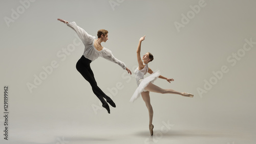 Gravity-defying motion. Ballet duet in poetic airborne movement, arms extended, legs reaching outward against white studio background. Concept of classic dance, passion, energy, rhythm.