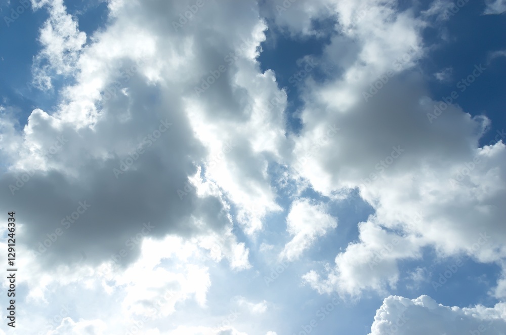 Fototapeta premium Thick clouds behind the hot sun. Beautiful white clouds in the bright blue sky as a natural concept.