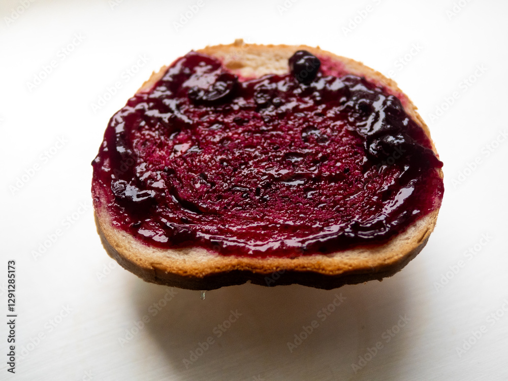 A slice of bread with a purple jelly on it A slice of bread with a purple jelly on it