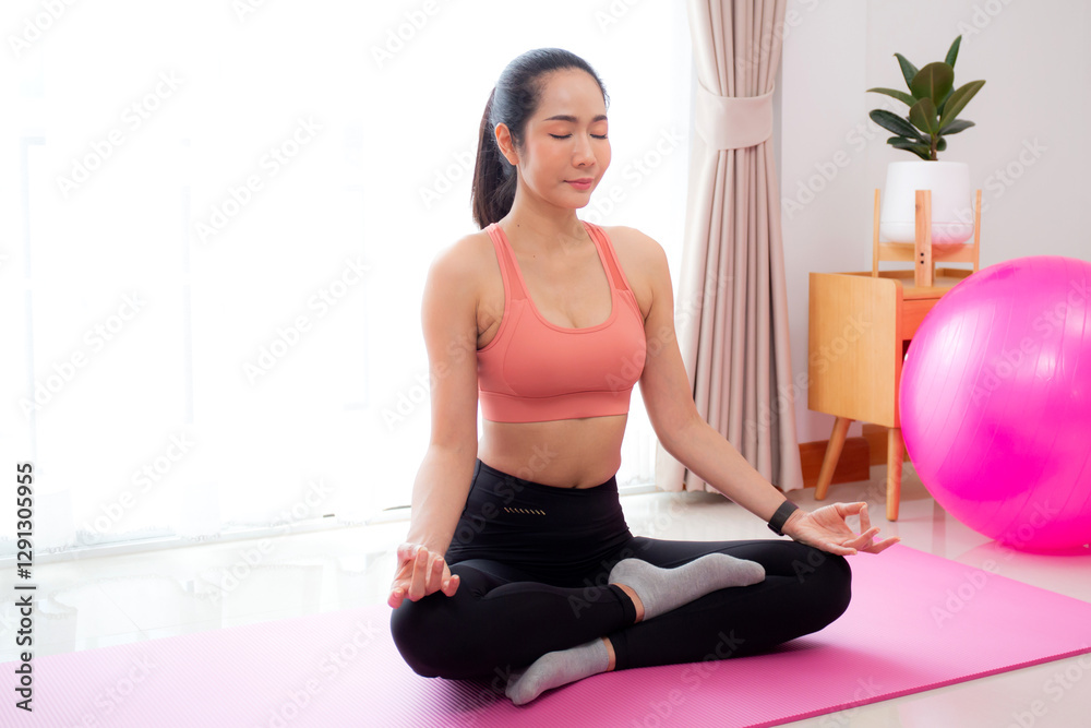 Fototapeta premium Young asian woman meditation sitting on mat in serene and tranquility with yoga posture lotus in living room at home, woman practice yoga with breathing balance for mindfulness, sport for health.
