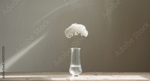 Small white flower in a simple vase placed on a wooden table with natural lighting in a cozy setting. photo