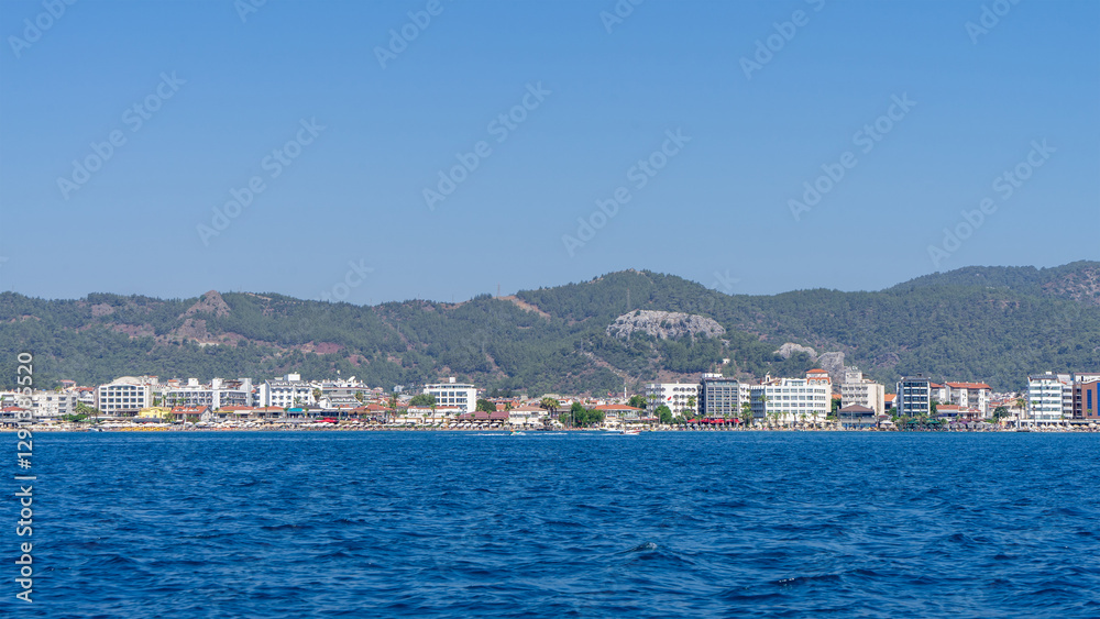 View from Mediterranean Sea on houses and hotels of city of Marmaris, Turkey on background of green hills and mountains