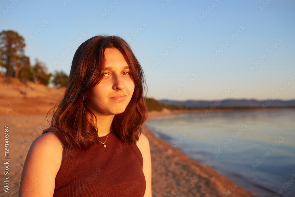 Portrait of an attractive girl on a sandy beach at sunset. Looking into the camera Portrait of an attractive girl on a sandy beach at sunset. Looking into the camera