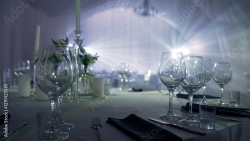 Empty glasses and cutlery on a table are waiting for guests, illuminated by soft, diffused light