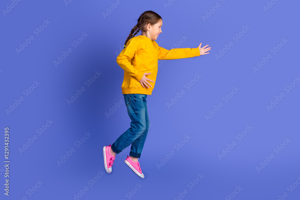 Full body image of a cheerful young girl in casual attire jumping actively against a solid purple studio background Full body image of a cheerful young girl in casual attire jumping actively against a solid purple studio background
