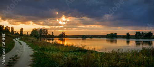 Beautiful panorama, dark clouds contrast with the warm light of the setting s...