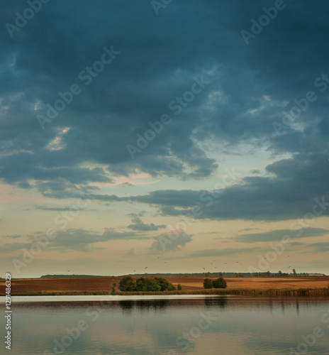 beautiful landscape of a pond and evening sky, view of fields on the opposite...