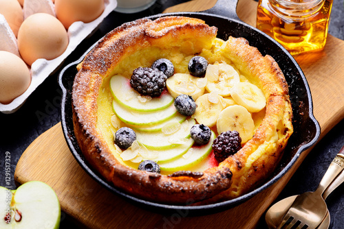 Dutch baby pancake with apples, banana, fresh berries powdered sugar and almonds.	 photo