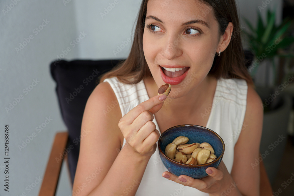 Healthy girl eating Brazil nuts as snack at home Healthy girl eating Brazil nuts as snack at home