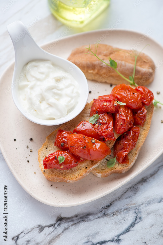 Beige plate with roasted tomato bruschettas and stracciatella cheese, vertical shot on a white granite surface, middle closeup Beige plate with roasted tomato bruschettas and stracciatella cheese, vertical shot on a white granite surface, middle closeup
